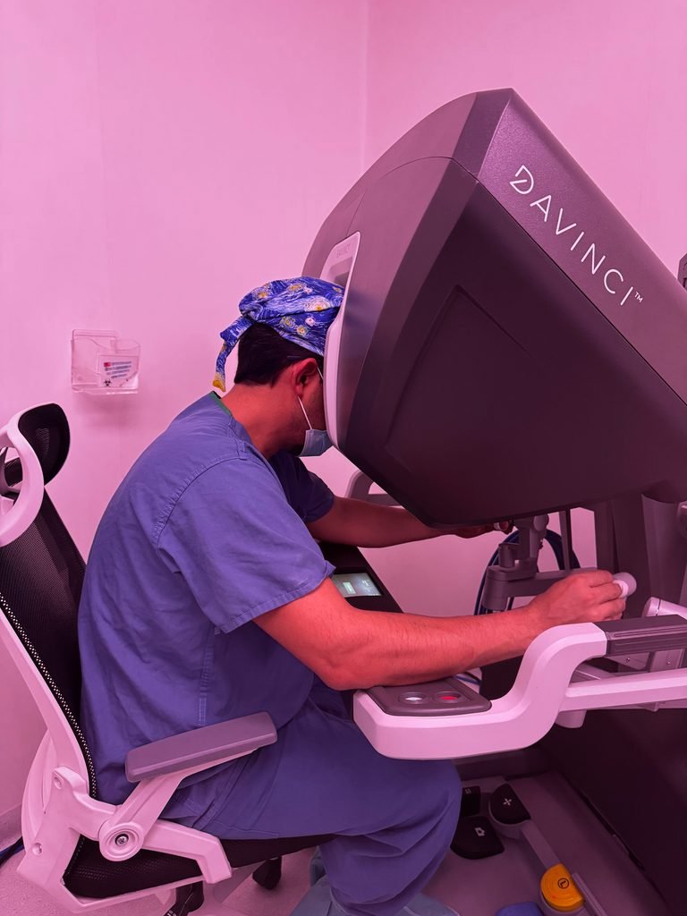 Dr. Benjamín Gloria Ávila utilizando la consola Da Vinci durante una cirugía robótica